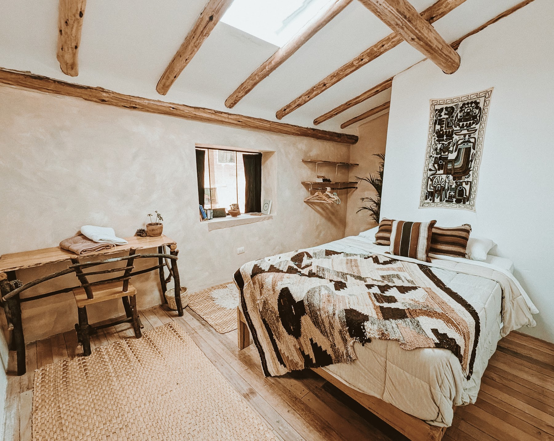 A light-filled bedroom with natural stone and wooden beams